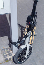 Load image into Gallery viewer, A photo of an escooter with an Abus Alarmbox 2.0 device attached. The scooter is locked to a post.