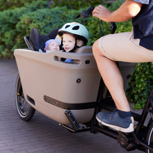 Load image into Gallery viewer, Lifestyle image of the Dolly Joy electric cargo bike showing a toddler and baby being transported in the cargo box.