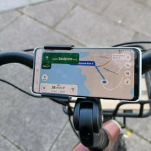Load image into Gallery viewer, A product image of the Kuma Paw Phone Holder showing a phone in position on the handlebars of a Kuma electric bike.