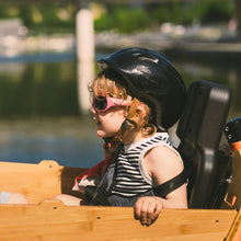 Load image into Gallery viewer, A lifestyle image showing the Yuba 2be3 child seat inside the Bamboo Box of the Yuba Supercargo CL electric cargo bike with a child passenger strapped into the seat.