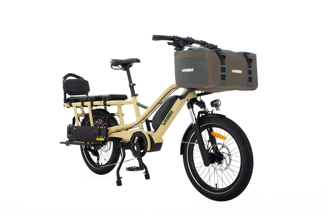 A product image of the Yuba Fastrack electric longtail cargo bike, showing the Latte frame colour option. The Grab and Go bag and soft top seat accessories are shown on the bike.