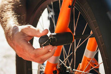 Load image into Gallery viewer, A photo of the Yuba Pin Lock being inserted through the front wheel of a Yuba longtail cargo bike.