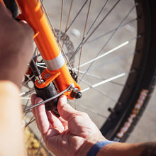 Load image into Gallery viewer, A photo of the Yuba Pin Lock being inserted through the front wheel of a Yuba longtail cargo bike.