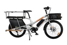Load image into Gallery viewer, A product image of the Yuba Kombi E5 electric longtail cargo bike which can be hired from LeaseBike. The photo shows the right side of the cargo bike. The photo shows two soft spot seats and a monkey bar accessory attached to the rear rack and a bread basket attached to the front of the bike.