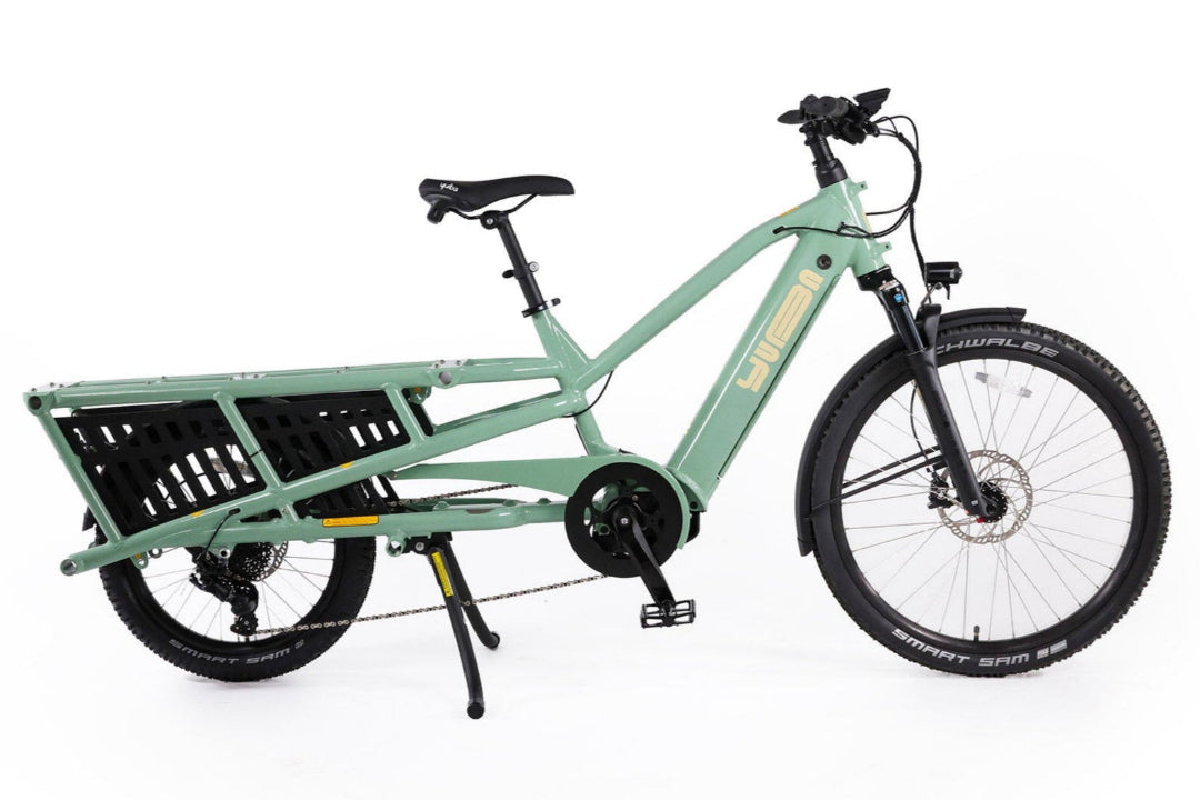 A product image of the Yuba Spicy Curry V4 electric longtail cargo bike. The frame colour is Lunar (a pale green colour) and the bike is in its basic set up, with no accessories attached.