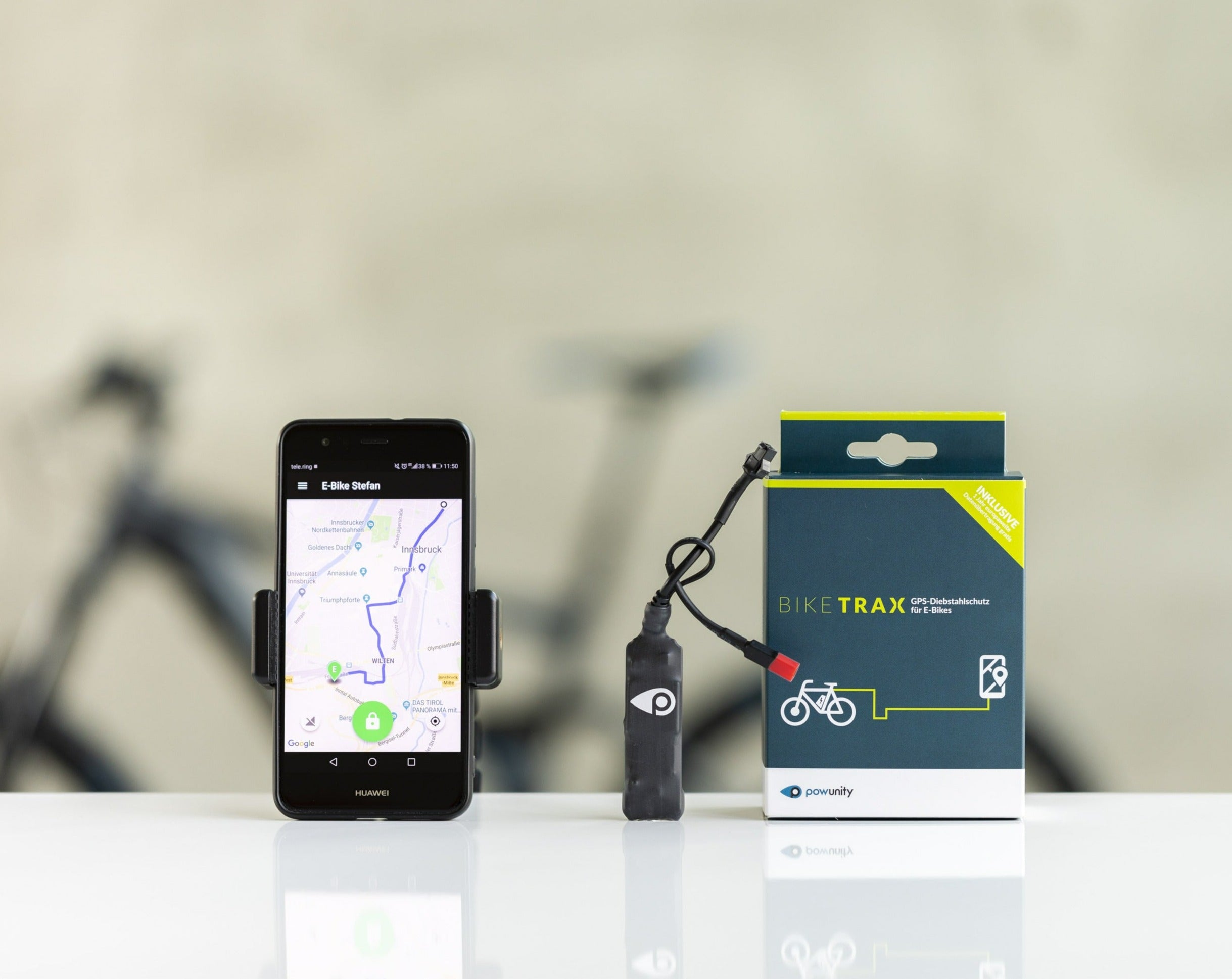 A GPS tracking device for bicycles, showing a smartphone displaying the tracking app and the product packaging box.
