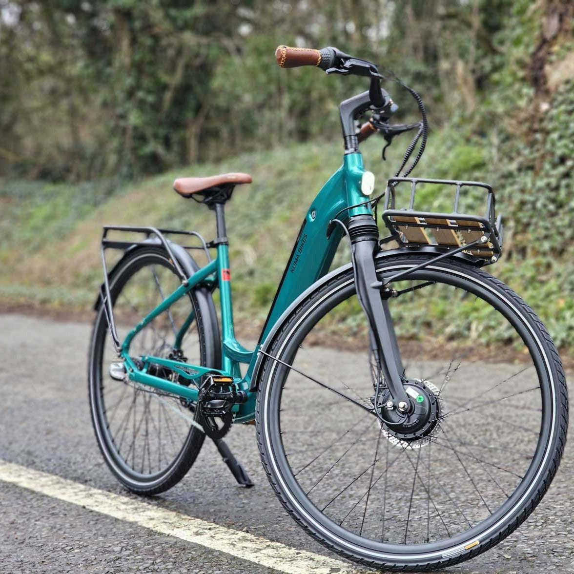A photo of the Kuma S2 electric bike on a country lane, parked in the middle of the road.The frame colour is Emerald Green..