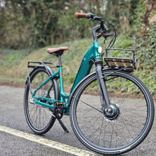 Load image into Gallery viewer, A photo of the Kuma S2 electric bike on a country lane, parked in the middle of the road.The frame colour is Emerald Green..
