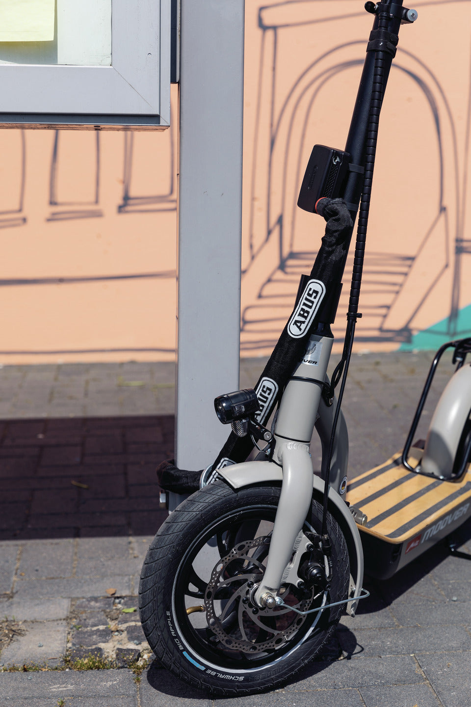 A photo of an escooter with an Abus Alarmbox 2.0 device attached. 