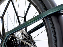 Load image into Gallery viewer, Close-up of a bicycle chain and frame with 'Novus' branding.
