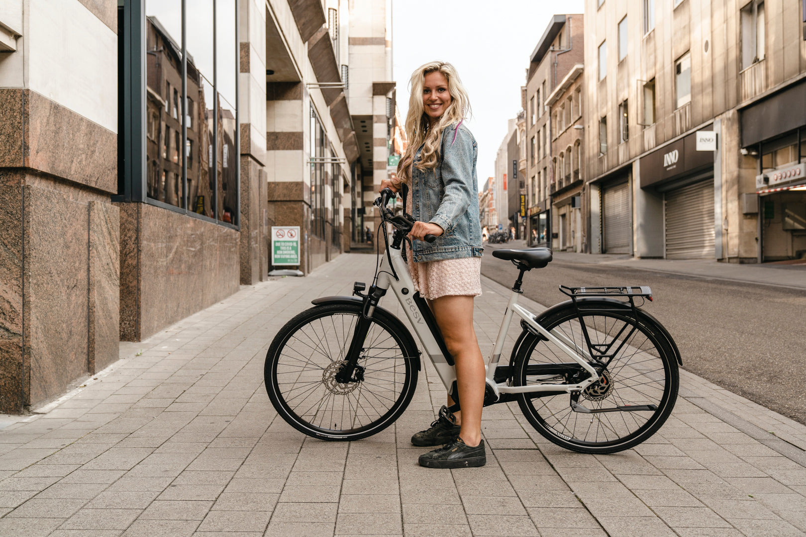 A lifestyle image of the BESV CT 2.2 LS electric bike taken on an urban street with a female model. 