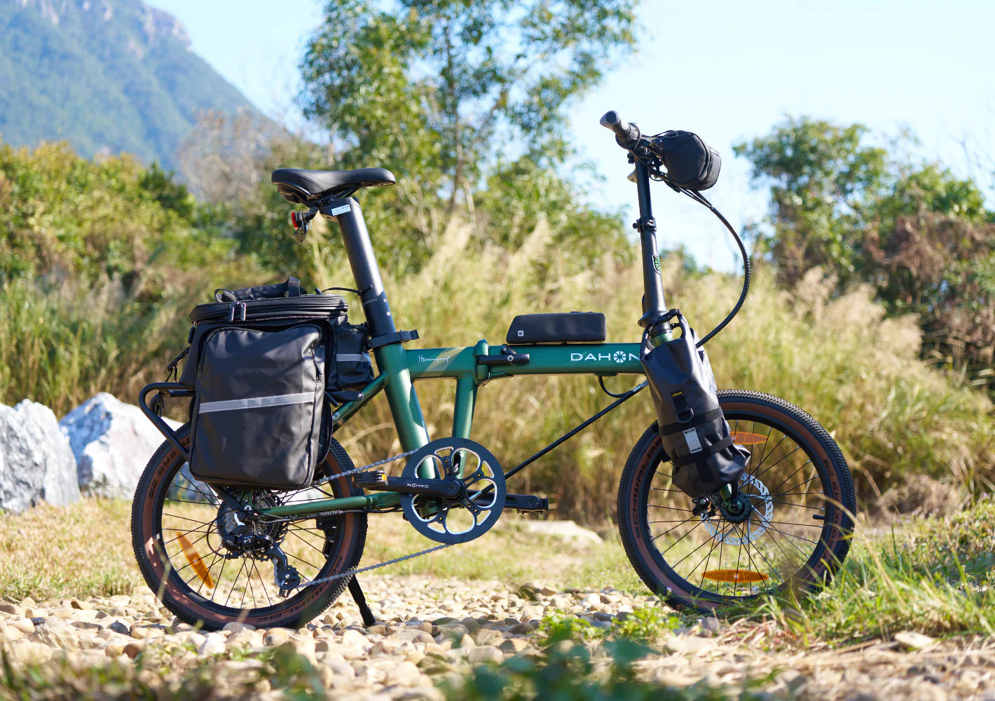 Green Dahon electric bike with a black bag on a natural landscape background