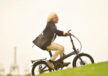 Load image into Gallery viewer, A lifestyle image of a Dahon Unio E20 folding electric bike with the frame colour obsidian. It is being ridden by a man up a steep incline.
