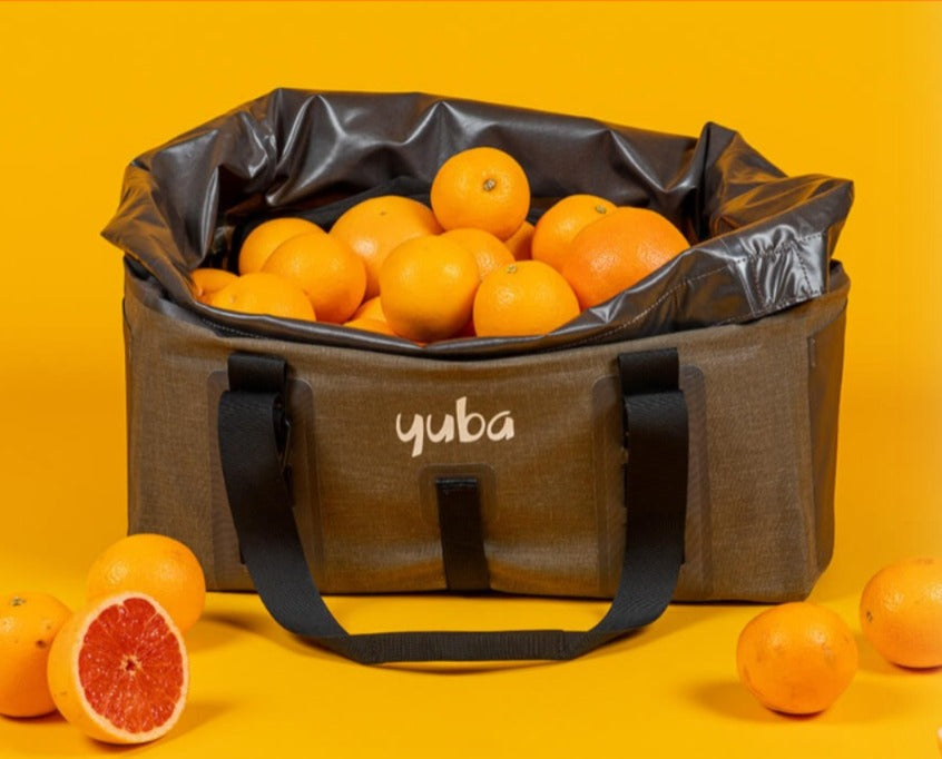 A product picture of the Yuba Grab & Go Bag. The bag is loaded with dozens of oranges to show its scale.