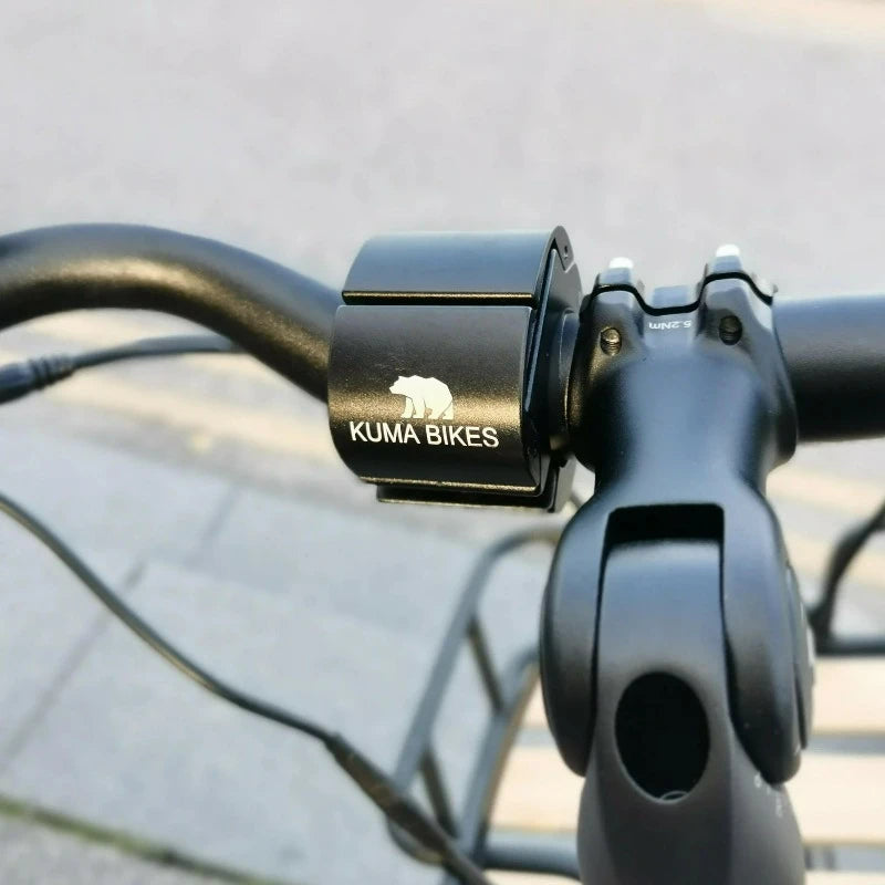 A product image of the Kuma Paw Phone Holder showing a phone in position on the handlebars of a Kuma electric bike.