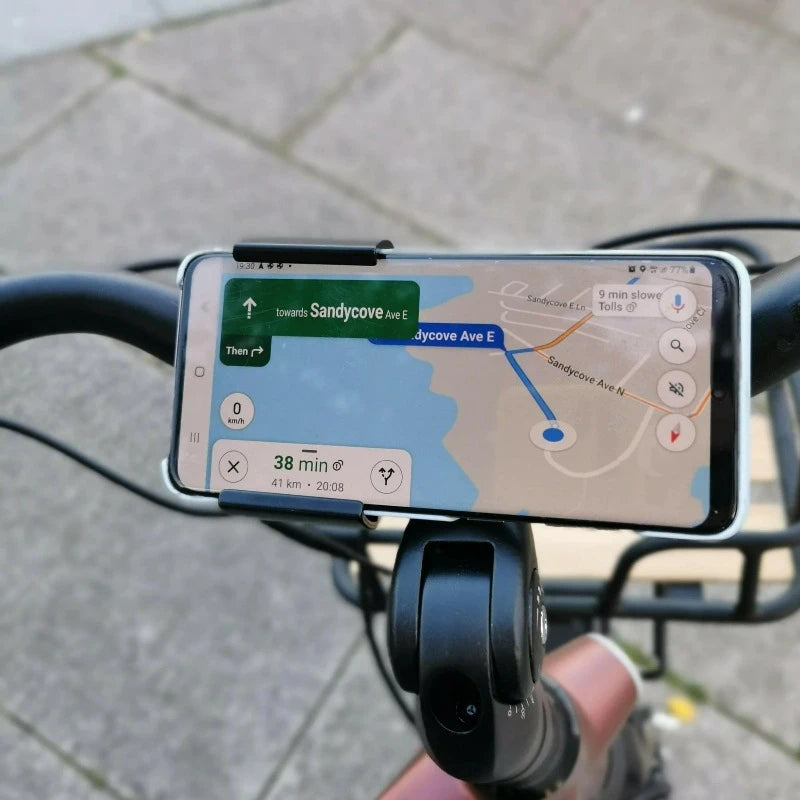 A product image of the Kuma Paw Phone Holder showing a phone in position on the handlebars of a Kuma electric bike.