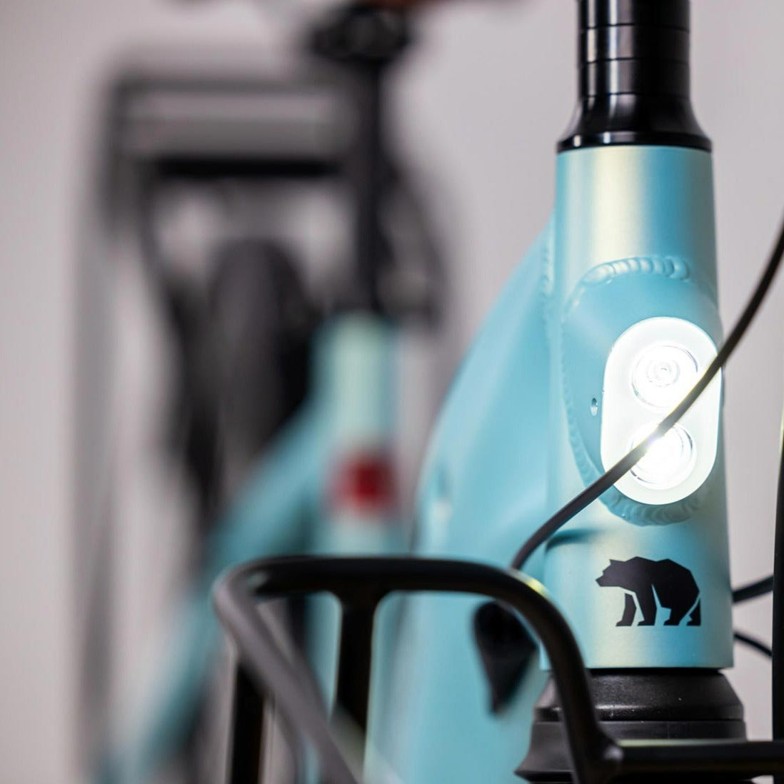 A close-up photo showing the detail of the integrated front light on the Glacier Blue frame of the Kuma S2 electric bike.