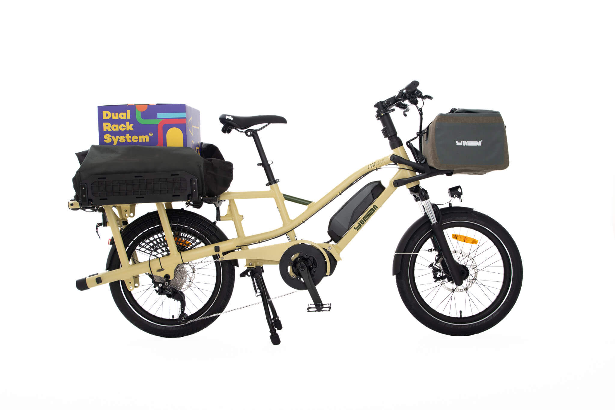 A product image of the Yuba Fastrack electric longtail cargo bike, showing the Latte frame colour option. The DRS bag and Grab and Go bag accessories are attached to the bike. 