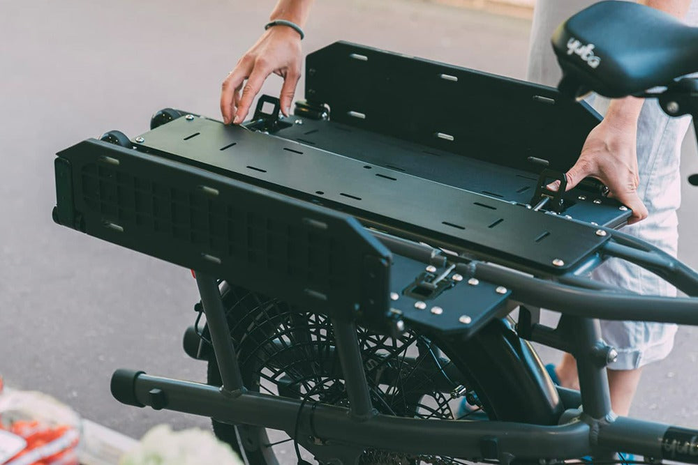 A product image of the Yuba FastRack Deck accessory which fits on the rear carrier of the Yuba FastRack electric longtail cargo bike. This shows the Deck in situ with the DRS loading system in the flatbed position.