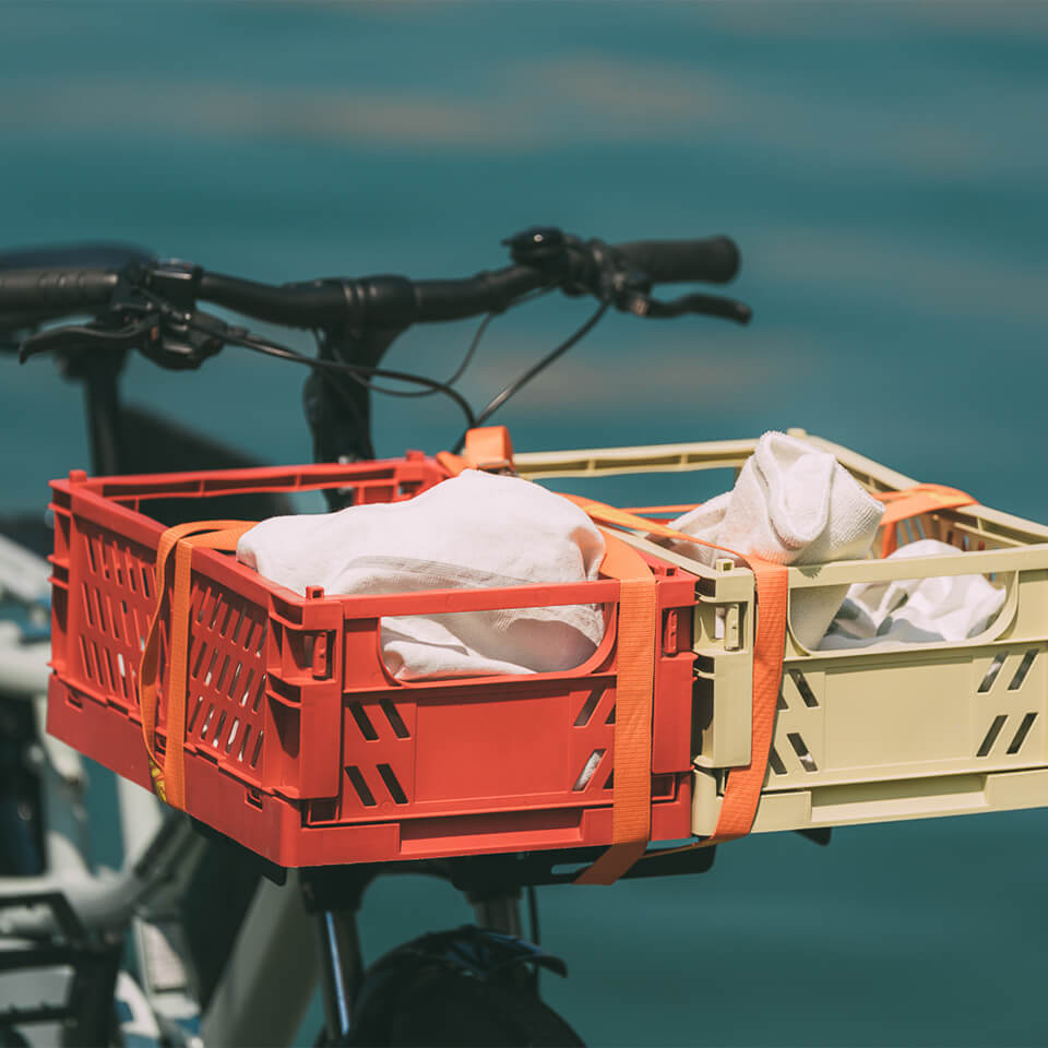 A photo of the Yuba Front Eco Deck attached to the front of a Yuba longtail cargo bike with two plastic crates strapped on top of the deck.