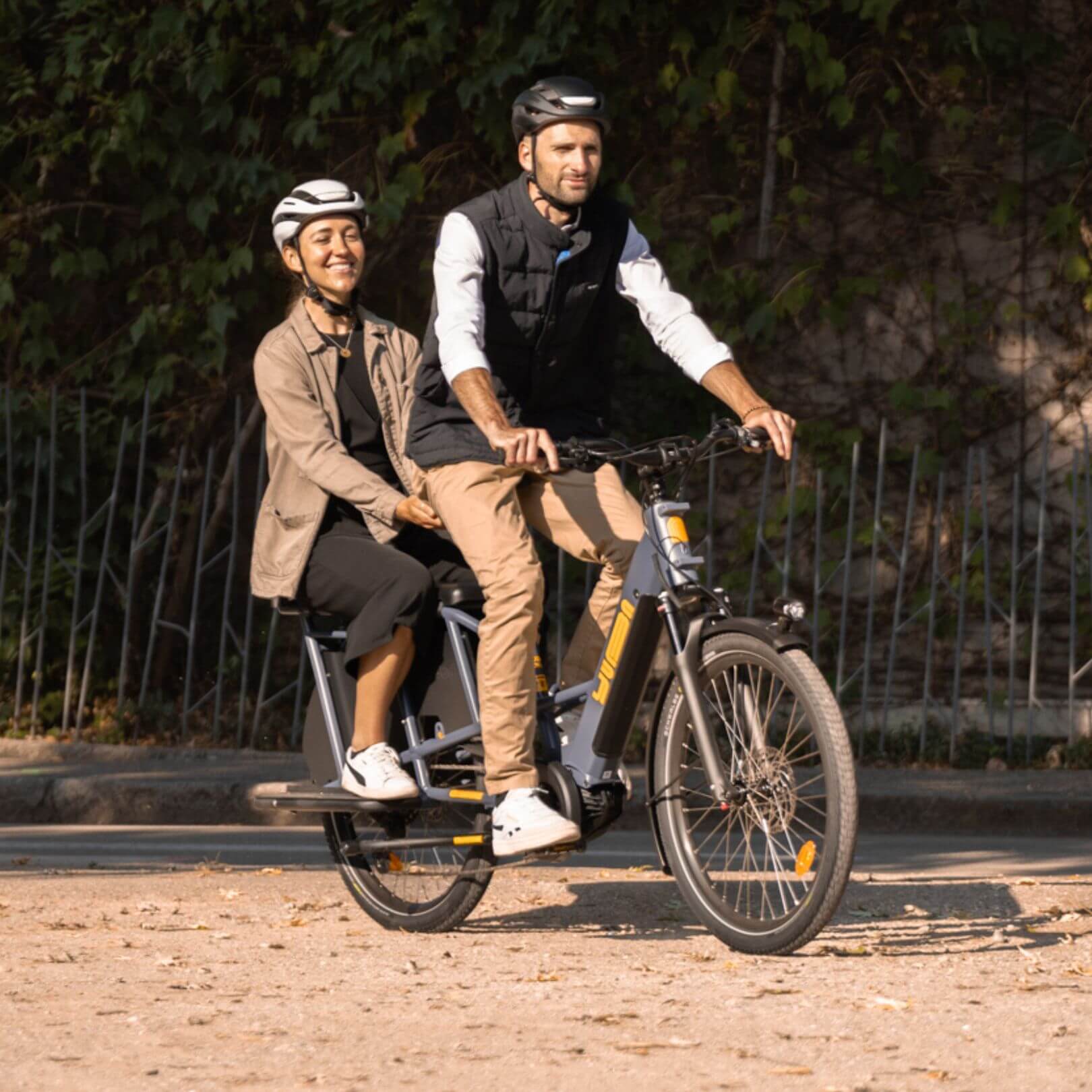 A lifestyle image of the Yuba Compact AlloyBoards accessory for Yuba compact longtail cargo ebikes, showing a rear passenger on a Yuba cargo bike. 