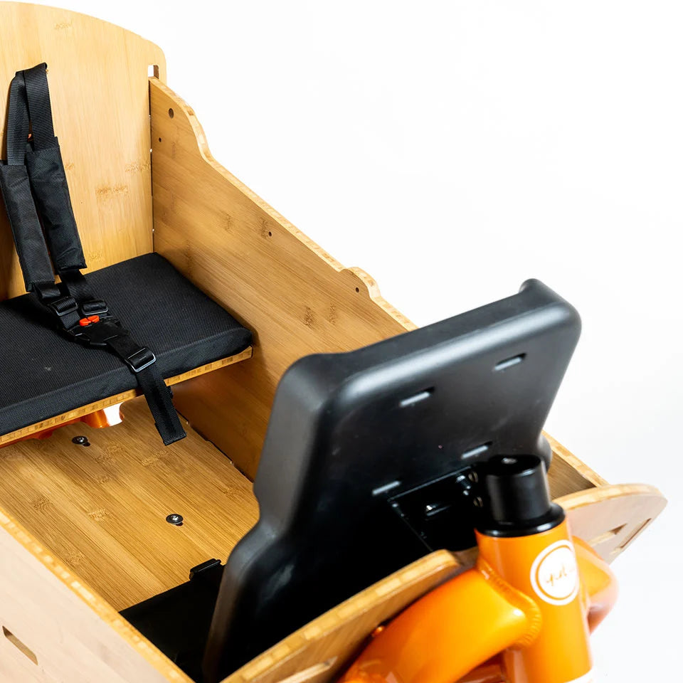 A product image showing the back side of the Yuba 2be3 child seat inside the Bamboo Box of the Yuba Supercargo CL electric cargo bike.