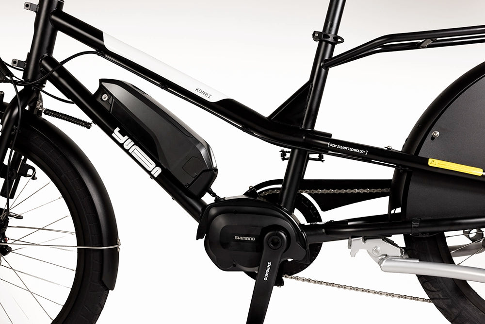A close-up image of the Yuba Kombi E6 electric longtail cargo bike showing the black frame, the battery and the electric motor.