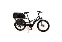 Load image into Gallery viewer, A product image of the Yuba Kombi E6 electric longtail cargo bike taken at an oblique angle from the front right of the bike. The bike has a wooftop basket attached to the rear rack, which is designed for carrying canine passengers. The bike has a black frame. 
