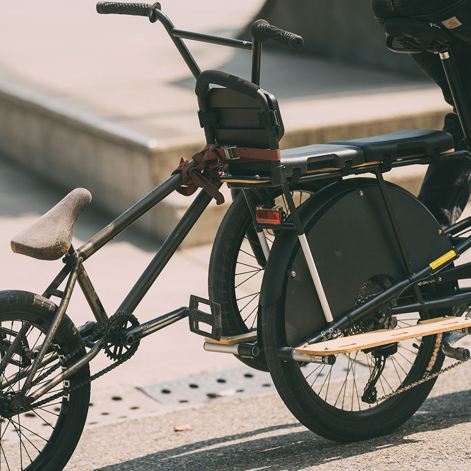 A photo showing another bike being loaded into the Yuba Kombi Tow Tray to enable it to be towed by a Yuba Kombi electric longtail cargo bike. 