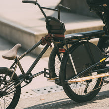 Load image into Gallery viewer, A photo showing another bike being loaded into the Yuba Kombi Tow Tray to enable it to be towed by a Yuba Kombi electric longtail cargo bike. 
