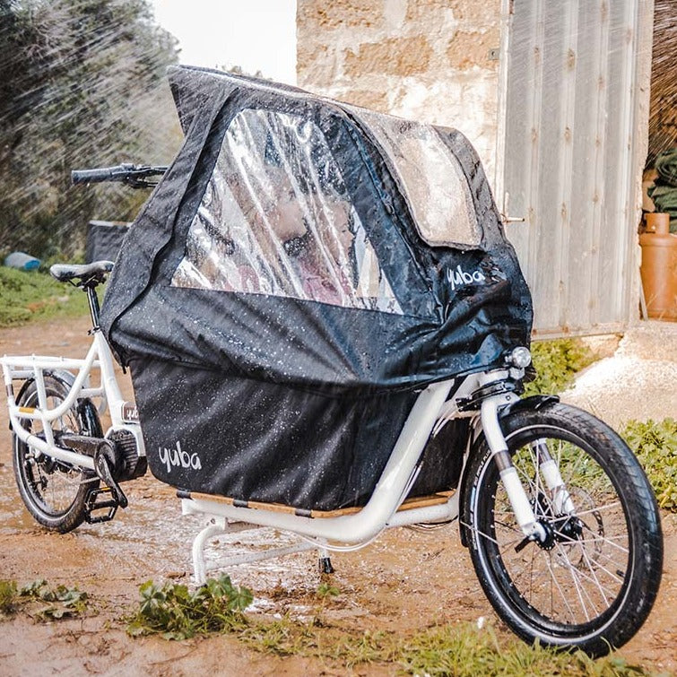 Yuba Supercargo Canopy product image showing the rain tent covering the cargo box on a white Yuba Supercargo CL electric cargo bike. The bike is outdoors on a rainy day.