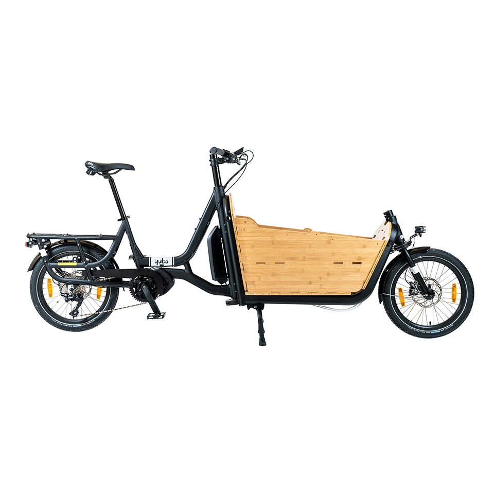 A product image of the Yuba Supercargo CL electric front-loading cargo bike. The model shown has a black frame and a bamboo box. The bike is available to buy from Bleeper. 