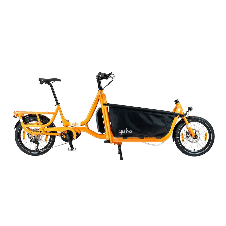 A product image of the Yuba Supercargo CL electric front-loading cargo bike. The model shown has an orange frame and a black canvas front box. The bike is available to buy from Bleeper.