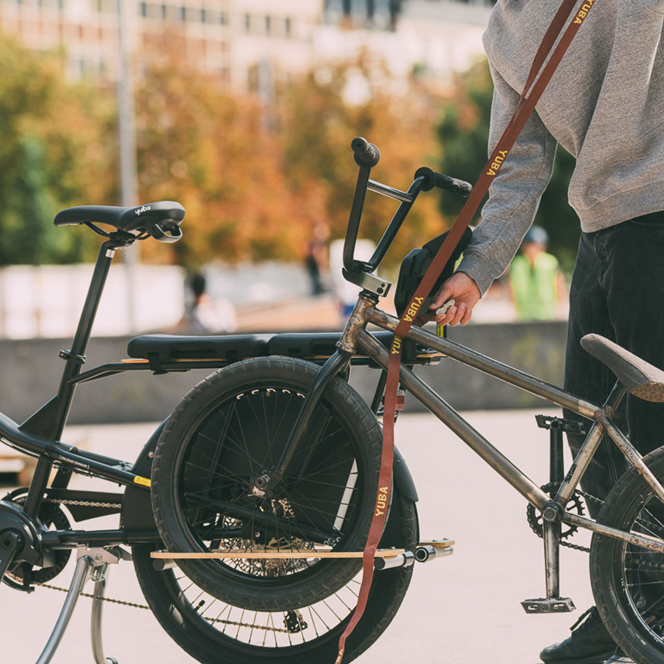 A photo showing another bike being loaded into the Yuba Kombi Tow Tray to enable it to be towed by a Yuba Kombi electric longtail cargo bike. 