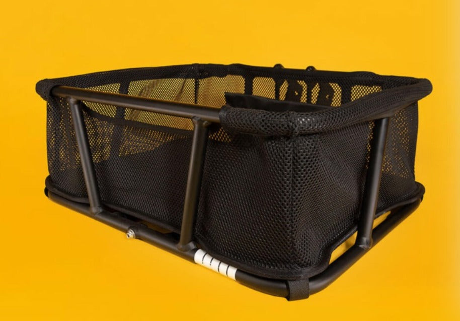 A product picture of the Yuba StuffRack front basket for Yuba longtail cargo bikes. The basket is photographed against an orange background.