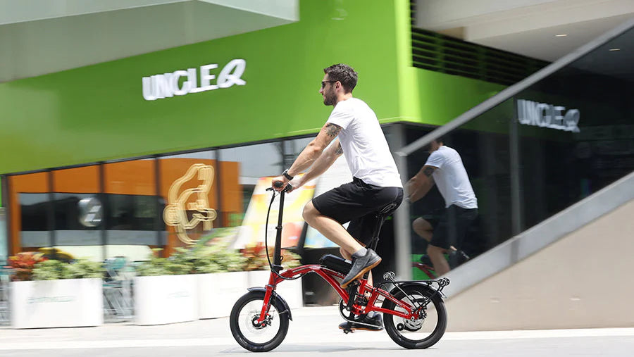 Person riding a small folding bicycle in front of a store.