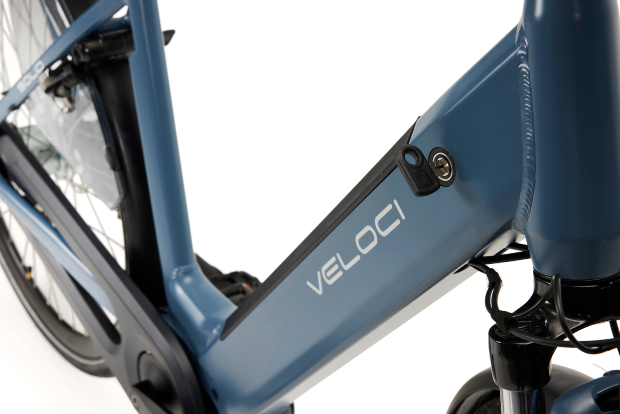 A close-up photo of the battery of the Veloci Solid electric bike. The battery is integrated into the downtube of the bike, and the key for removing the battery is shown in the lock on the downtube. 