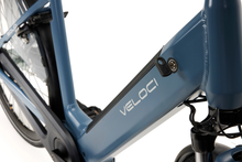 Load image into Gallery viewer, A close-up photo of the battery of the Veloci Solid electric bike. The battery is integrated into the downtube of the bike, and the key for removing the battery is shown in the lock on the downtube. 
