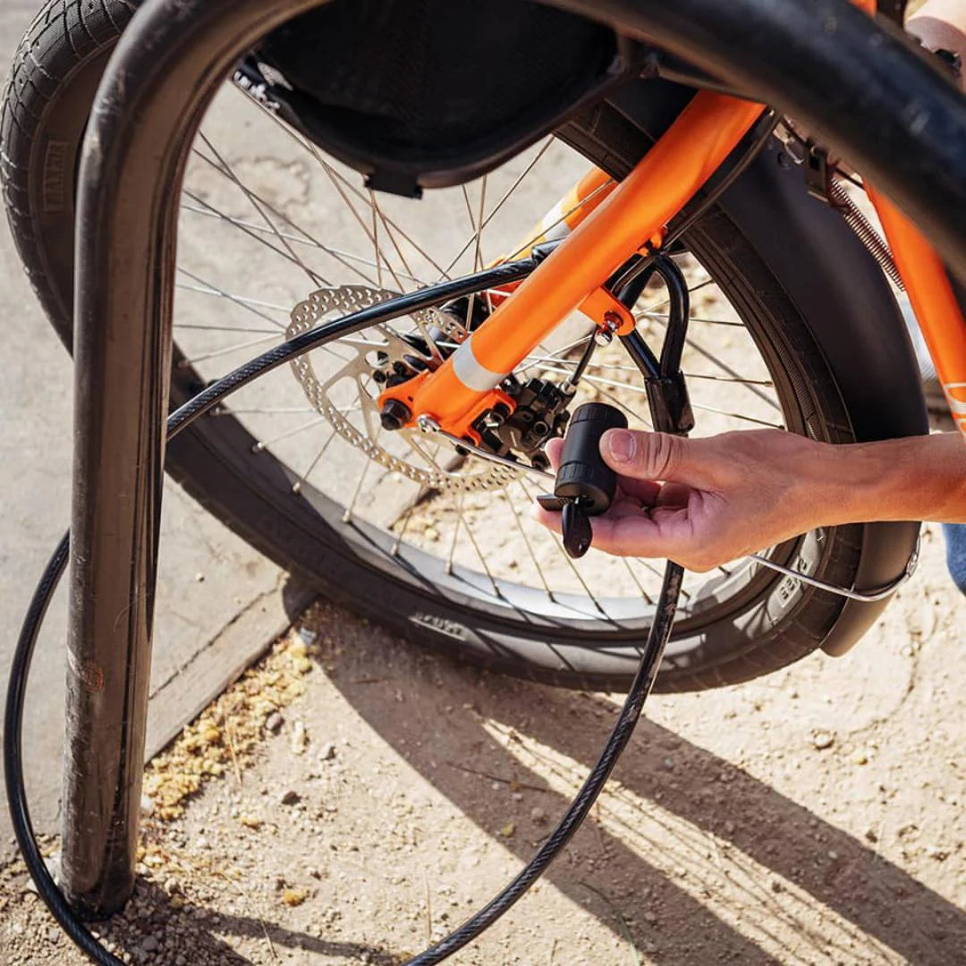 A product image of the Yuba Cable Lock in use, being used to secure a cargo bike to a cycle parking stand.